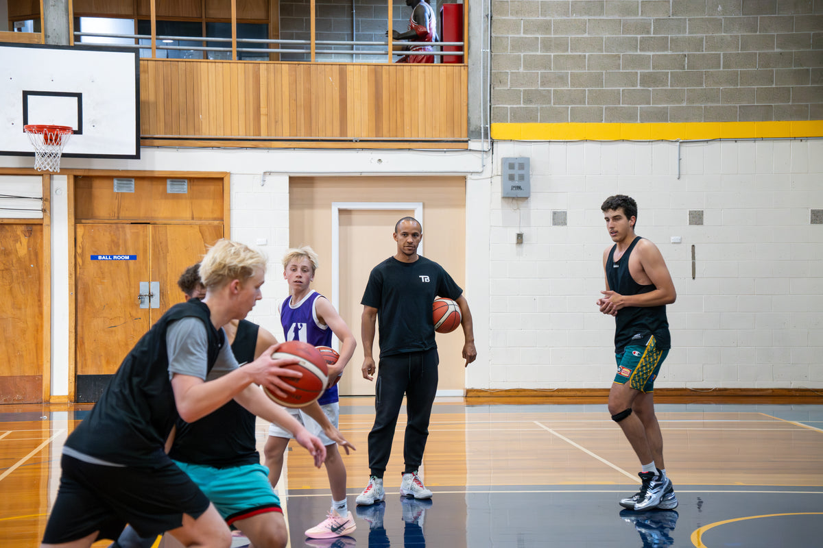 Tiri coaching a player through a basketball drill